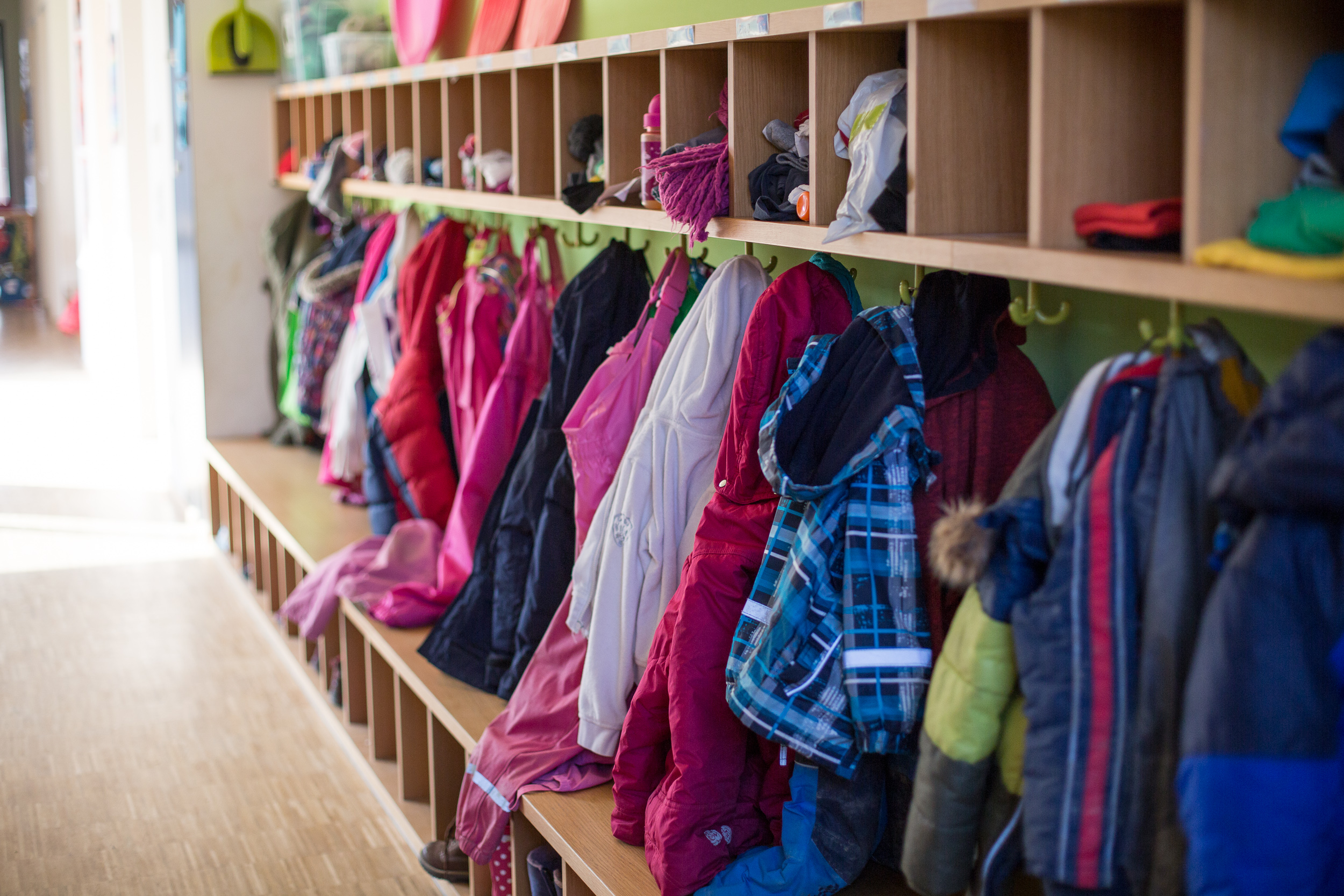 Garderobe im Kindergarten: Eine Reihe bunte Jacken hängen am Haken
